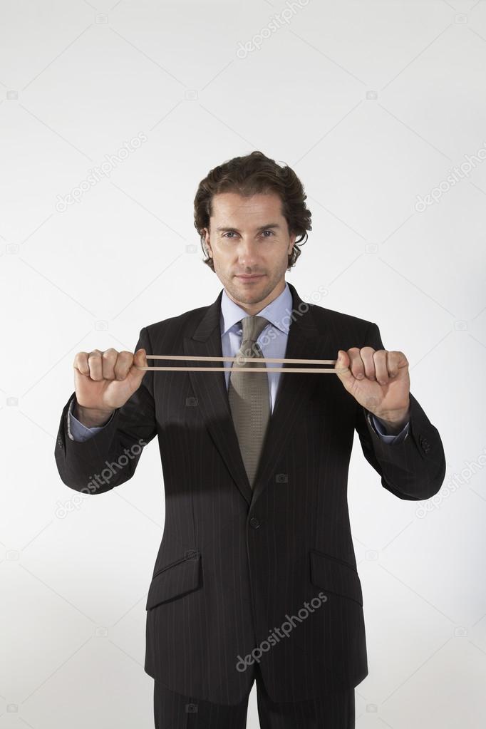 Businessman stretching rubber band