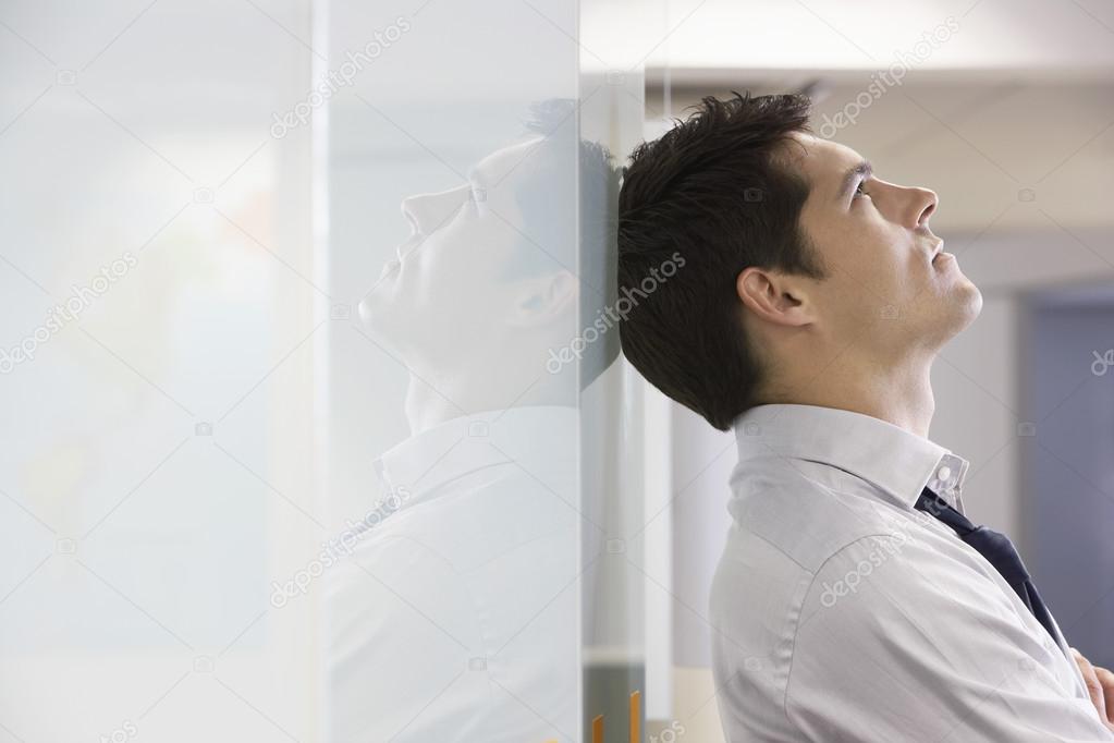 Unhappy Businessman leaning back against wall