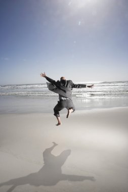 Enthusiastic Businessman Jumping on the Beach clipart
