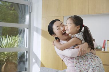 Smiling Woman Hugging her Daughter clipart