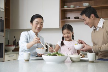 Couple and daughter eating a meal clipart