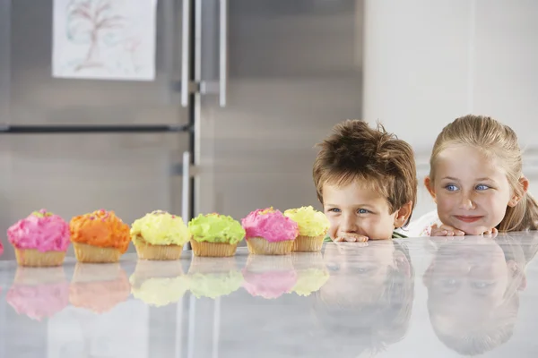 Kinder blicken auf Cupcakes — Stockfoto