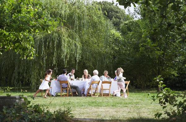 Família comendo à mesa no jardim — Fotografia de Stock
