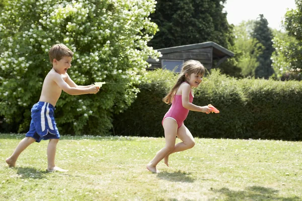 Pojke skytte flicka med vatten pistol — Stockfoto