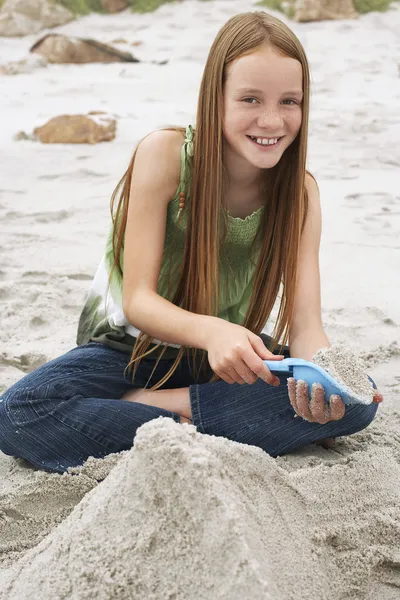 Meisje spelen in zand op het strand — Stockfoto