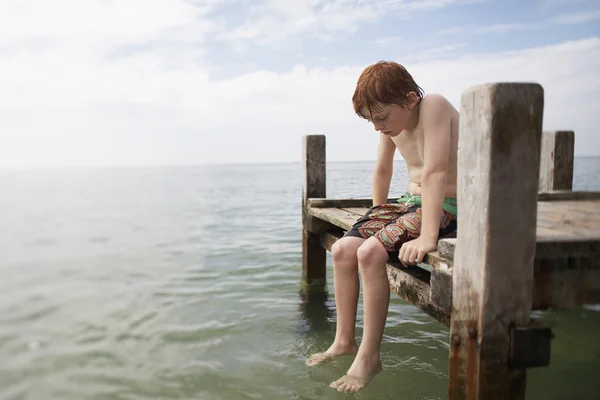 Pre-teen jongen zittend op de pier — Stockfoto