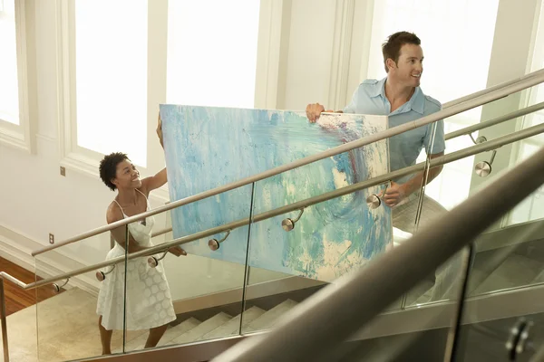 Couple moving modern painting up stairs — Stock Photo, Image