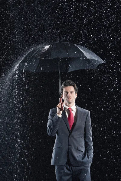 Бизнесмен, стоящий под крепким зонтом — стоковое фото