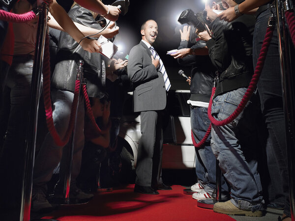 Man on red carpet in front of paparazzi