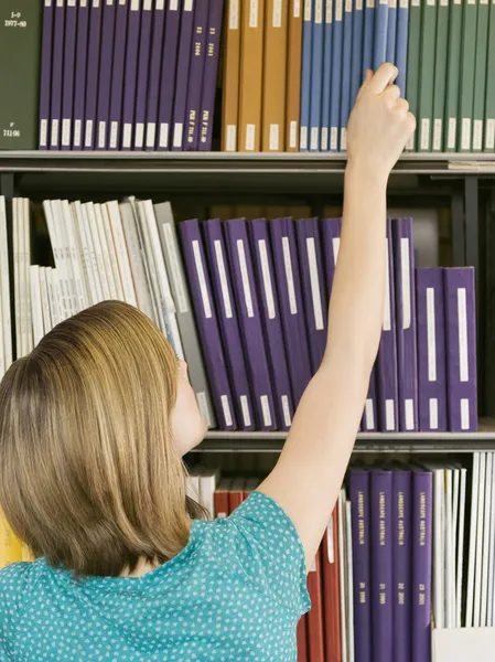 Girl reaching for book — Stock Photo, Image