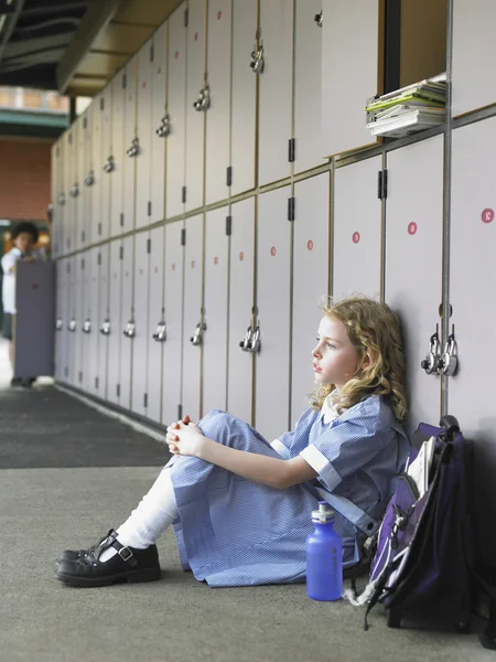 Elementaire schoolmeisje zittend op de vloer — Stockfoto