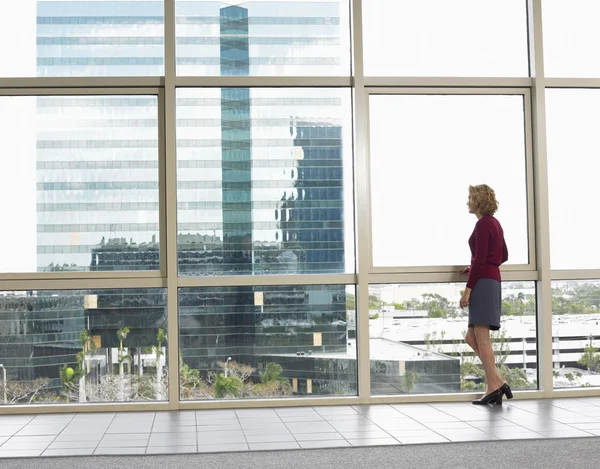 Businesswoman looking out of office building — Stock Photo, Image