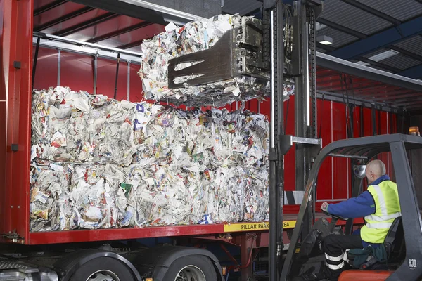 Homem em pilhas de carga de veículos de papel reciclado — Fotografia de Stock