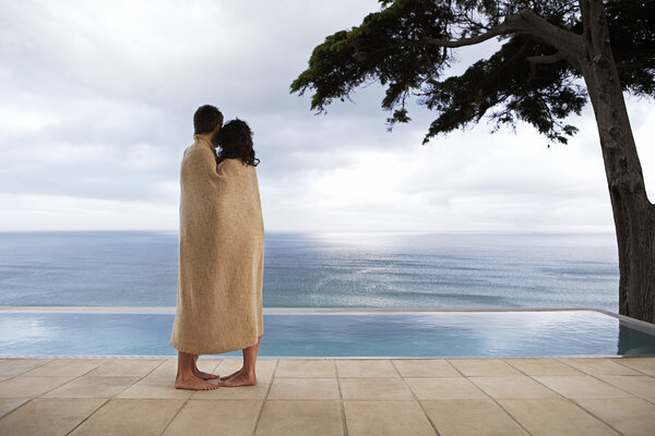 Couple covered in towel by pool