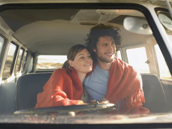 Couple wrapped in blanket in van — Stock Photo, Image