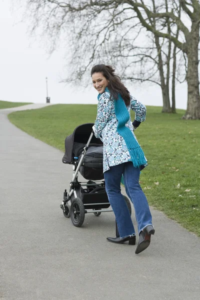 Mamma driftigt barnvagn i park — Stockfoto