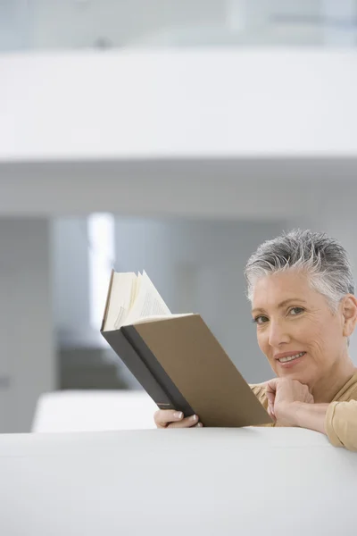 Frau liest Buch auf Sofa — Stockfoto