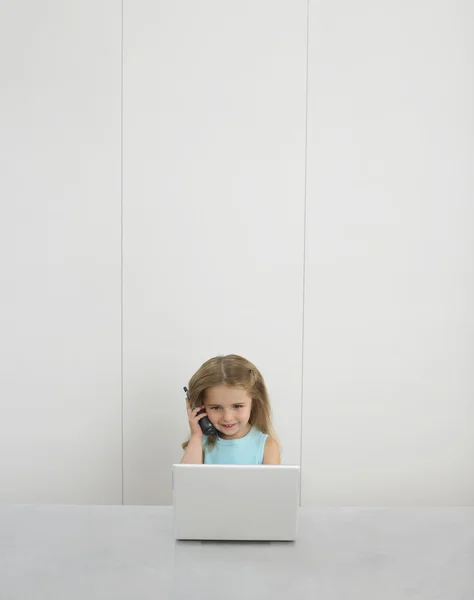 Menina usando telefone celular e laptop — Fotografia de Stock