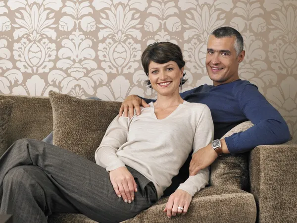 Happy couple sitting on sofa — Stock Photo, Image