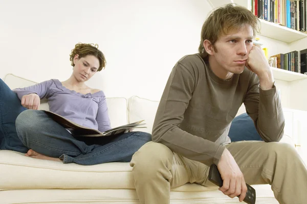 Homem assistindo televisão com mulher lendo — Fotografia de Stock