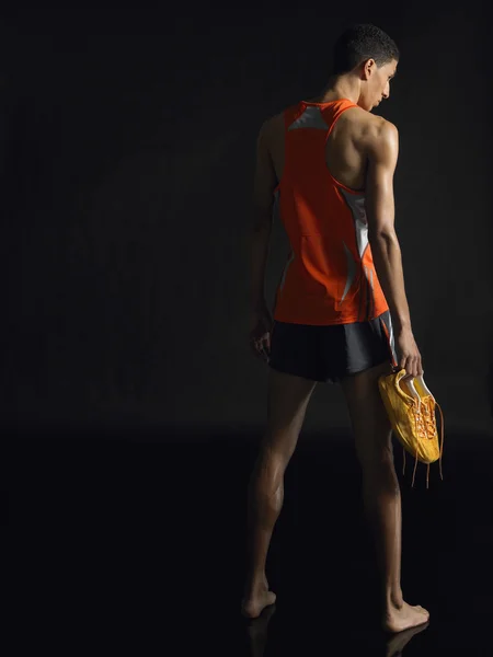 Athlete holding shoes — Stock Photo, Image