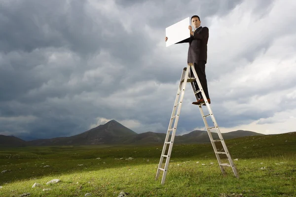 Affärsman som står på en stege — Stockfoto