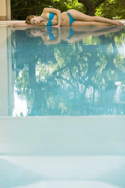 Mujer acostada junto a la piscina — Foto de Stock
