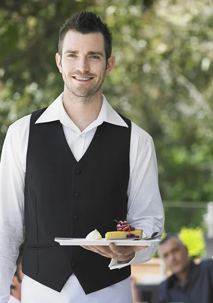 Waiter holding slice of pie at cafe — Stock Photo, Image