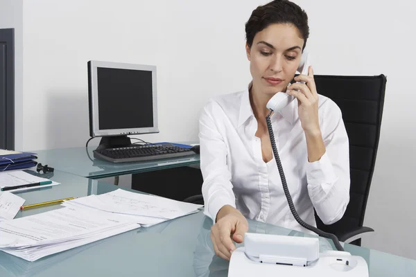 Businesswoman dialling telephone in office — Stock Photo, Image