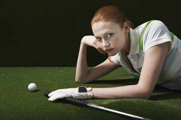 Kvinna liggande på golvet med golf club — Stockfoto