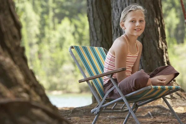 Flicka sitter på solstol i skogen — Stockfoto