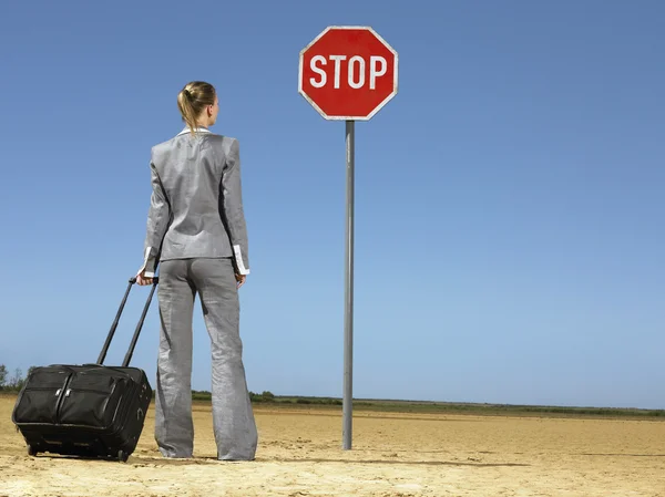 Geschäftsfrau mit Gepäck vor Stoppschild — Stockfoto