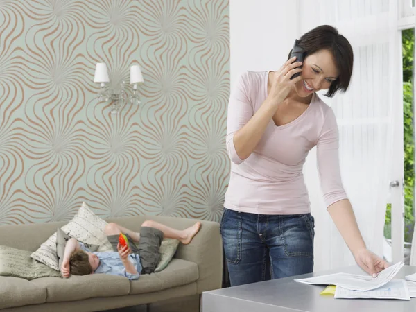 Woman using cell phone boy playing with toy — Stock Photo, Image