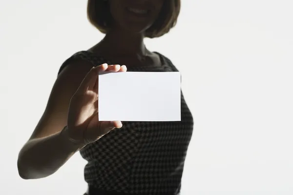 Smiling silhouetted woman holding blank card — Stock Photo, Image