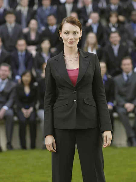 Business woman standing in front of people — Stock Photo, Image
