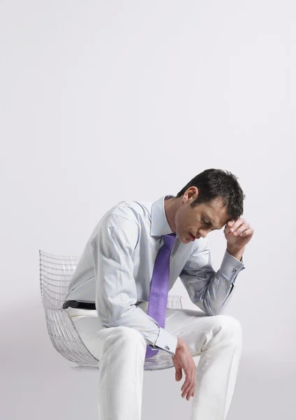 Man sitting in chair with head in hand — Stock Photo, Image