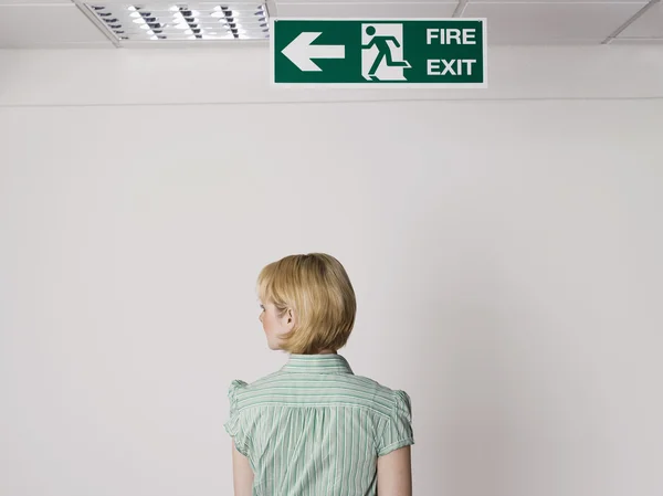 Businesswoman under exit sign — Stock Photo, Image