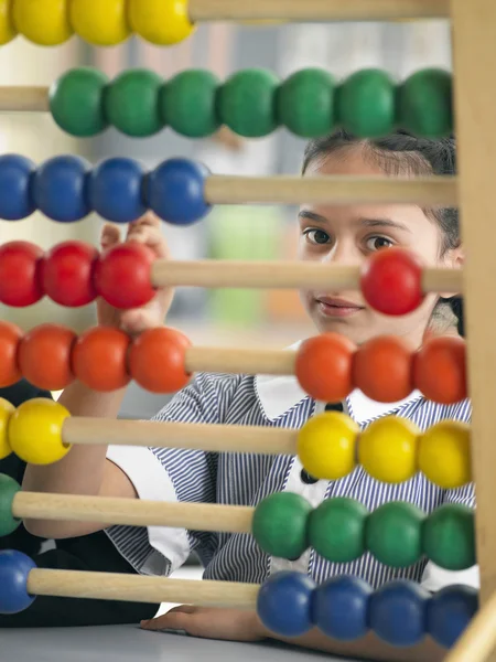 Elementaire schoolmeisje kijken door abacus — Stockfoto