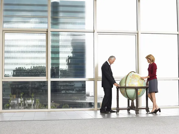 Businessman and woman studying large globe — Stock Photo, Image