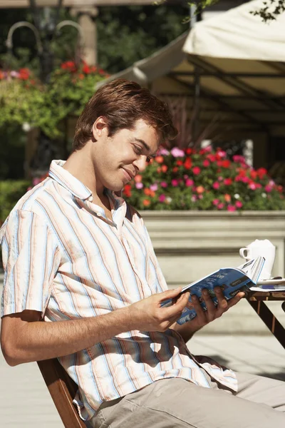 Человек в кафе, читающий путеводитель — стоковое фото