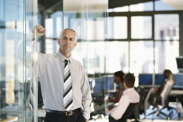 Businessman leaning on door in office — Stock Photo, Image