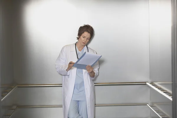 Physician Reviewing Notes in elevator — Stock Photo, Image