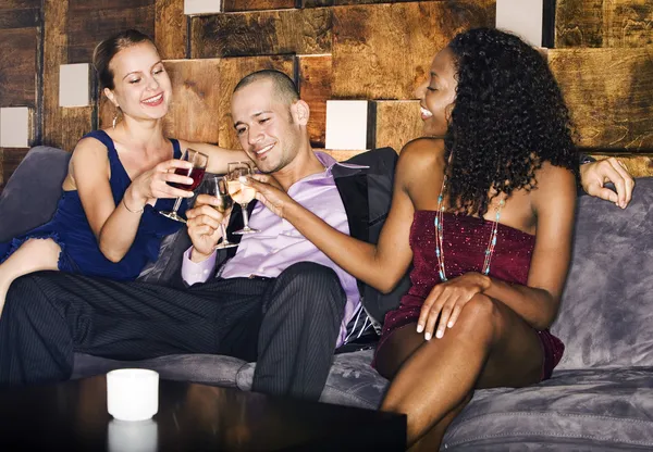 Hombre con dos mujeres sentadas en el sofá en el bar —  Fotos de Stock