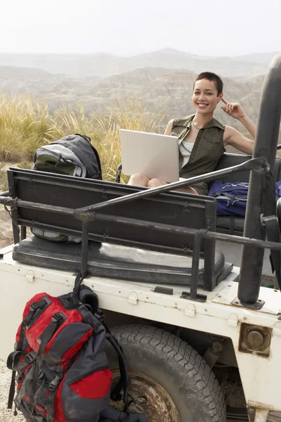 Woman using laptop on car — Stock Photo, Image