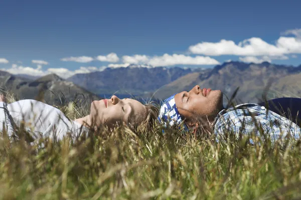 Man and woman lying in field — Stock Photo, Image