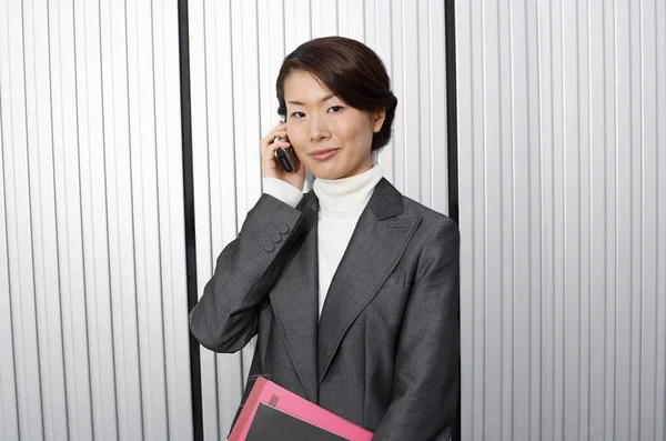 Podnikatelka drží papírování pomocí mobilního telefonu — ストック写真