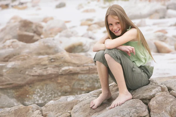 Menina sentada na rocha na praia — Fotografia de Stock