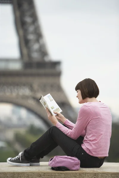 Woman reading book in front of Eiffel Tower — Stock Photo, Image