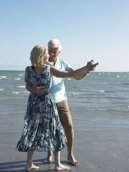 Старшая пара танцует на пляже — стоковое фото