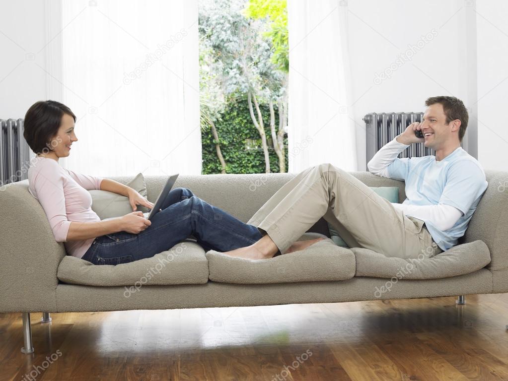 Couple reclining on couch — Stock Photo © londondeposit 33831077